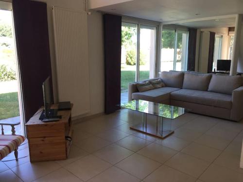 uma sala de estar com um sofá e uma mesa de vidro em Maison d'architecte paisible em Cestas