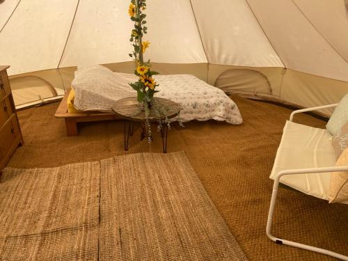 une tente avec une table et un vase de fleurs dans l'établissement Bluebell bell tent The Roaches, à Upper Hulme