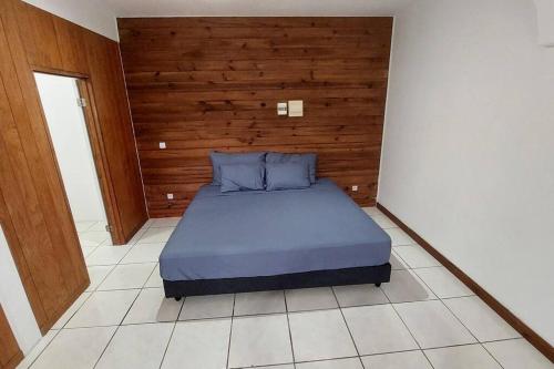 a bedroom with a blue bed with a wooden wall at Moorea Maharepa Appartement in Paraoro