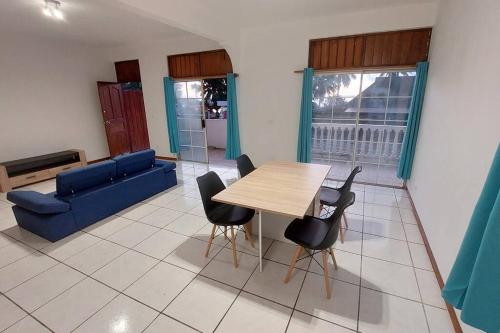 a living room with a table and chairs and a blue couch at Moorea Maharepa Appartement in Paraoro