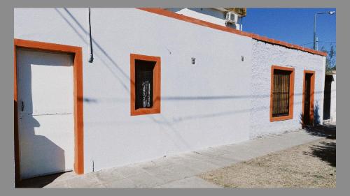 un edificio blanco con ventanas de color naranja y una puerta en Bethel en Salta