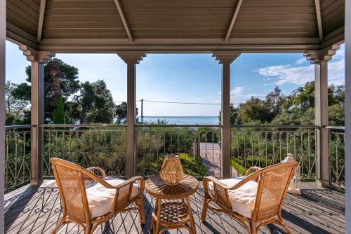 a porch with chairs and a table and a view of the ocean at Sunset English Villas in Patra