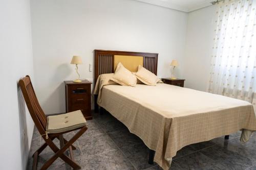 a bedroom with a bed with a chair and two tables at Lo Raconet de Júlia in Vinaròs