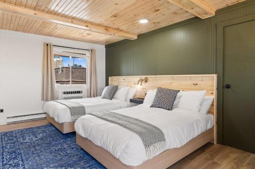 two beds in a bedroom with green walls and a window at The Boha Hotel in Lake Placid
