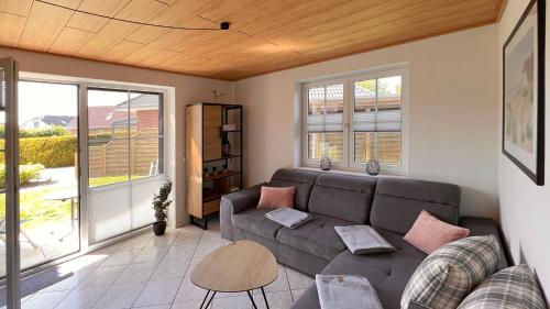 a living room with a couch and two windows at Ferienwohnung am Sonnenstrahl in Dorum Neufeld