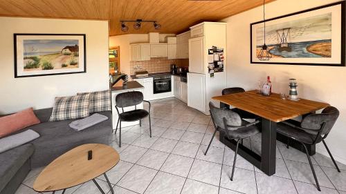 ein Wohnzimmer und eine Küche mit einem Tisch und einem Sofa in der Unterkunft Ferienwohnung am Sonnenstrahl in Dorum Neufeld