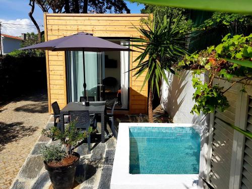 a patio with a table and an umbrella and a pool at 205 Serenity in Cascais