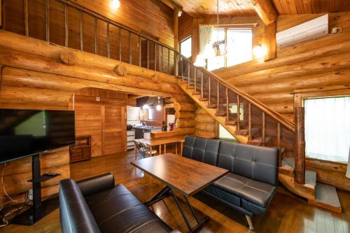 a living room with a table and a staircase at ログハウスGrazzi in Nasu-yumoto