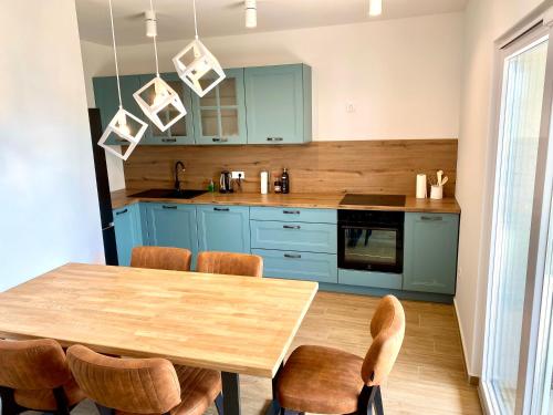 una cocina con armarios azules y una mesa y sillas de madera. en Apartmani Ferdinanda en Kustići