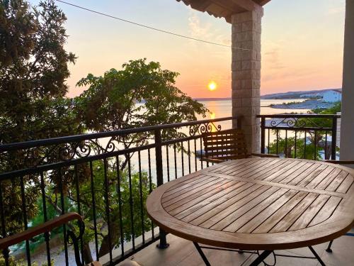 una mesa de madera en un balcón con puesta de sol en Apartmani Ferdinanda en Kustići