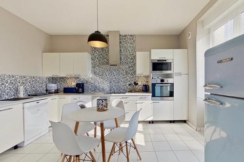 une cuisine avec des armoires blanches et une table et des chaises dans l'établissement BELLE VISNONIA meublé de caractère Sud Morbihan, à Béganne