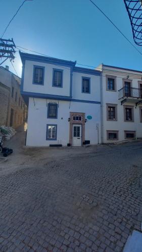 een groot wit gebouw aan een bakstenen straat bij Nil House Ayvalık in Ayvalık