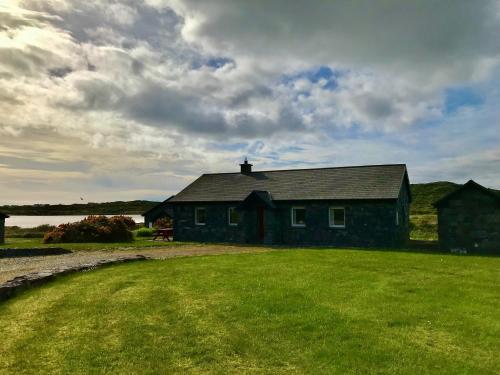 a house on a field with a grass yard at Kilronan Cottage in Ballyconneely