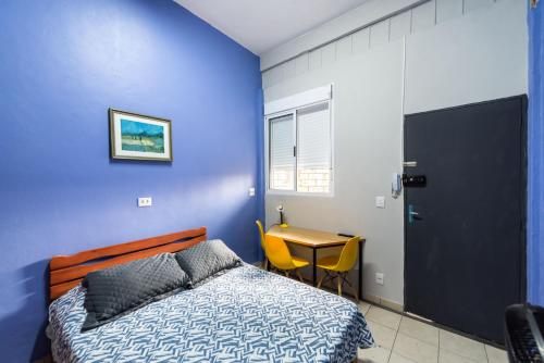 - une chambre bleue avec un lit et une table dans l'établissement Galeria Apartamentos, à São Paulo