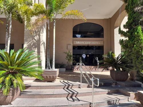 a hotel with palm trees in front of a building at Flat INCRIVEL na Vila Olimpia in Sao Paulo