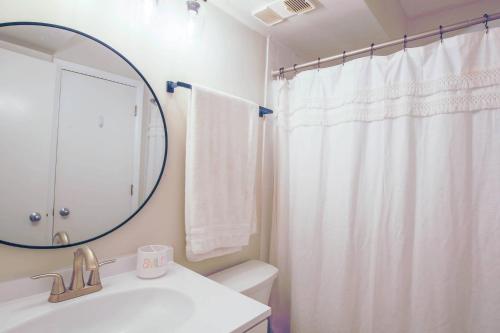 a bathroom with a white shower curtain and a mirror at Ocean Therapy in Isle of Palms