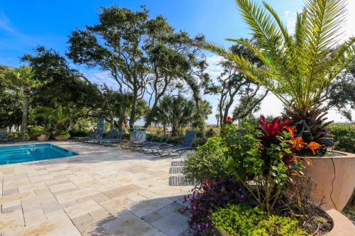 a patio with a pool and chairs and plants at Ocean Therapy in Isle of Palms