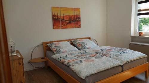 a bed in a room with a painting on the wall at Große helle Ferienwohnung mit Balkon, ruhig gelegen mit guter Verkehrsanbindung in Bad Berneck im Fichtelgebirge