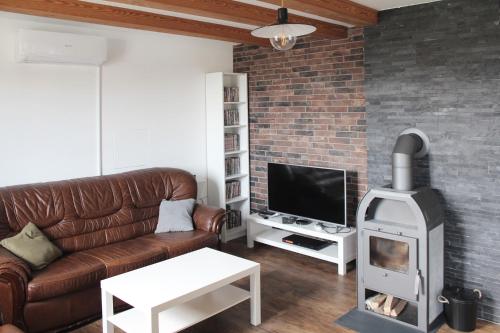 salon ze skórzaną kanapą i piecem opalanym drewnem w obiekcie Apartment Charlie w mieście Kamnik