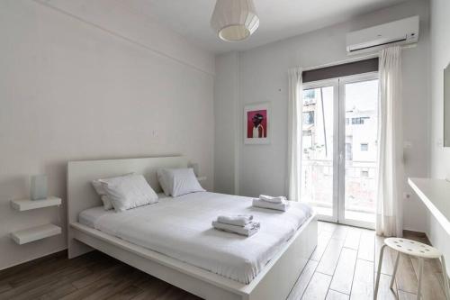 a white bedroom with a large bed and a window at Mariners Friend in Piraeus