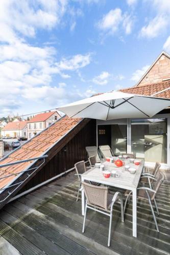 a table and chairs with an umbrella on a deck at Le repaire de Camille - LOFT in Birkenwald