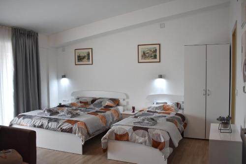 um quarto branco com 2 camas e uma cadeira em Ohrid Sunlight em Ohrid