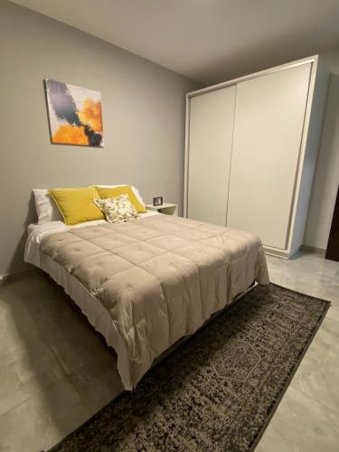 um quarto com uma cama grande e uma almofada amarela em Departamento de lujo tipo dúplex em Ciudad del Este