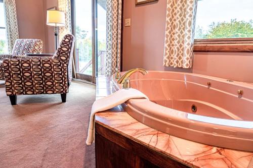 uma casa de banho com uma banheira grande e uma cadeira. em Point Au Roche Lodge em Plattsburgh
