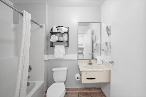 a white bathroom with a toilet and a sink at Beach Tower Beachfront Hotel, a By The Sea Resort in Panama City Beach