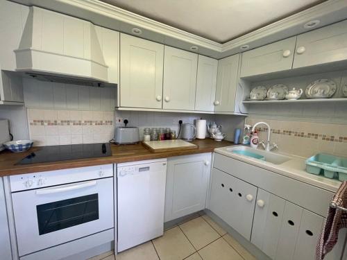 a kitchen with white cabinets and white appliances at Minehead Forget me not Cottage in Minehead