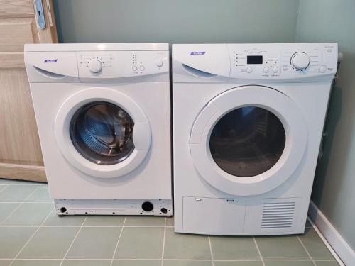 zwei nebeneinander sitzende weiße Waschmaschinen in der Unterkunft Gîte Les Tongs des Près, au cœur du Parc Normandie Maine in Livaie