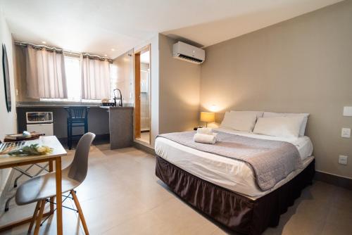 a bedroom with a bed and a desk and a kitchen at HMG Rio Suítes in Rio de Janeiro