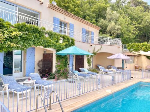 una piscina con sillas y sombrillas junto a una casa en Les Volets Bleus en Spéracèdes