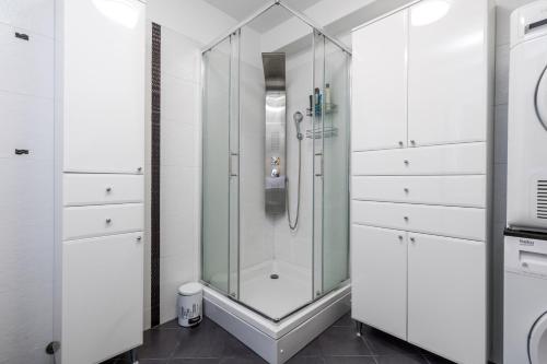 a glass shower in a bathroom with white cabinets at SkyRiver in Rijeka