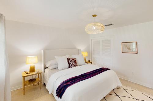 a white bedroom with a large bed and two lamps at Sunset on the Coast in Gulf Breeze