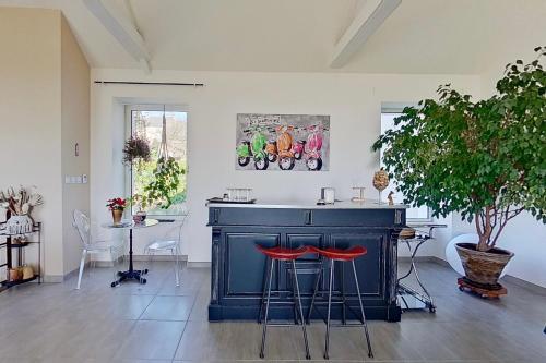 une cuisine avec un îlot bleu avec deux tabourets rouges dans l'établissement BELLE VISNONIA B&B gluten free & traditional, à Béganne