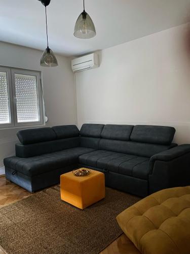 a living room with a black couch and an orange stool at Apartment in Shtip in Štip