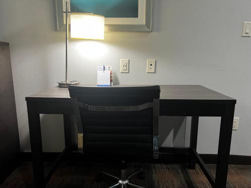 a desk with a chair and a lamp in a room at Baymont by Wyndham Bryan College Station in Bryan
