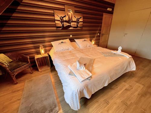 a bedroom with a large white bed with a wooden wall at Burgemeestershof in Wetteren