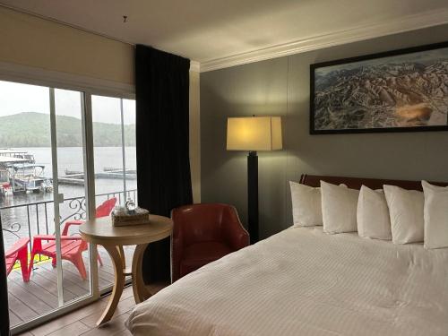 ein Hotelzimmer mit einem Bett, einem Tisch und einem Balkon in der Unterkunft Gauthier's Saranac Lake Inn in Saranac Lake