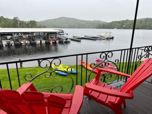 two red chairs sitting on a deck near a body of water at Gauthier's Saranac Lake Inn in Saranac Lake