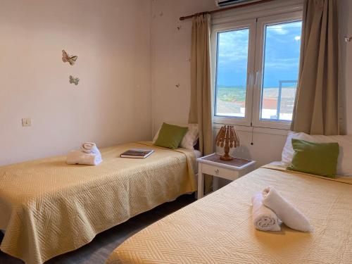 two beds in a room with a window at Family Country House-Corfu Holidays in Kanakádes