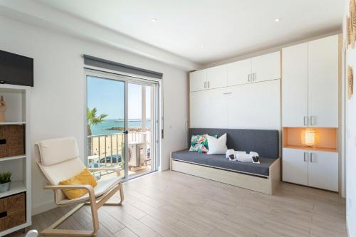 een woonkamer met een bank en uitzicht op de oceaan bij Stunning Studio with Beach Front- Astro Quarteira by Centralgarve in Quarteira