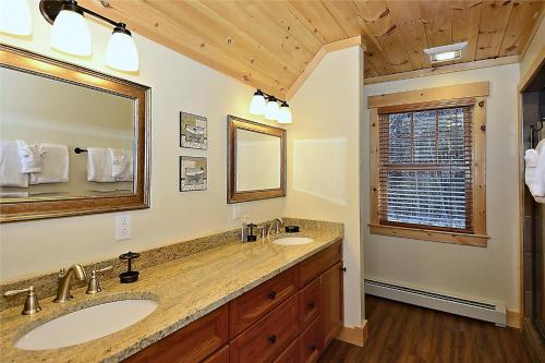 La salle de bains est pourvue de 2 lavabos et d'un grand miroir. dans l'établissement Lazy Bear Lodge, à Morrisville