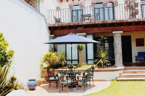 eine Terrasse mit einem Tisch, Stühlen und einem Sonnenschirm in der Unterkunft Villa Orbayu B&B Boutique in Cuernavaca