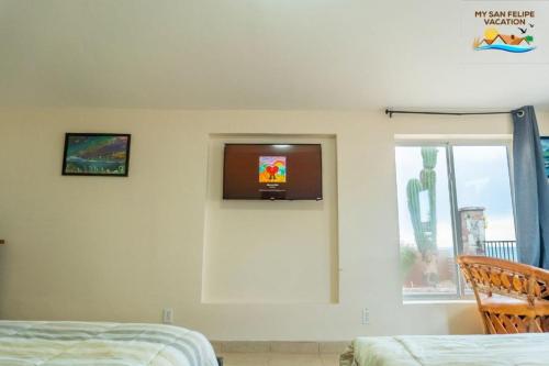 a bedroom with a tv on the wall and a window at Rancho Percebu Beach Studio 4 in Don Pancho
