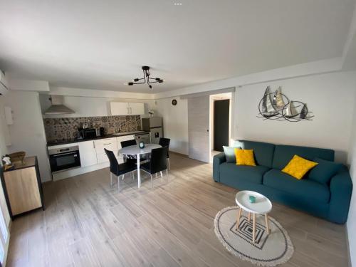 un salon avec un canapé bleu et une cuisine dans l'établissement Petite maison Valras-Plage, à Valras-Plage