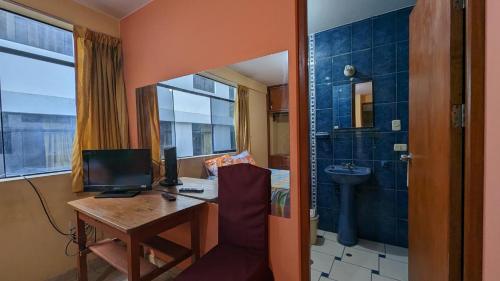 a room with a desk with a computer and a bathroom at Hospedaje Arequipa in Ayacucho