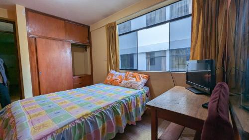 a bedroom with a bed and a desk with a television at Hospedaje Arequipa in Ayacucho