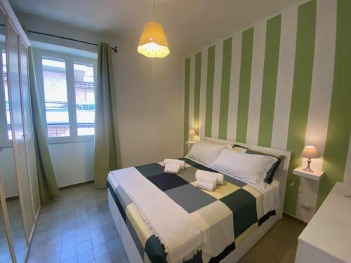 a bedroom with a bed with green and white stripes at Home Romana Centro Nettuno in Nettuno